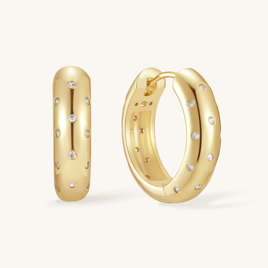 Gold-tone hoop earrings with small clear sparkle stones, oval hoop design
