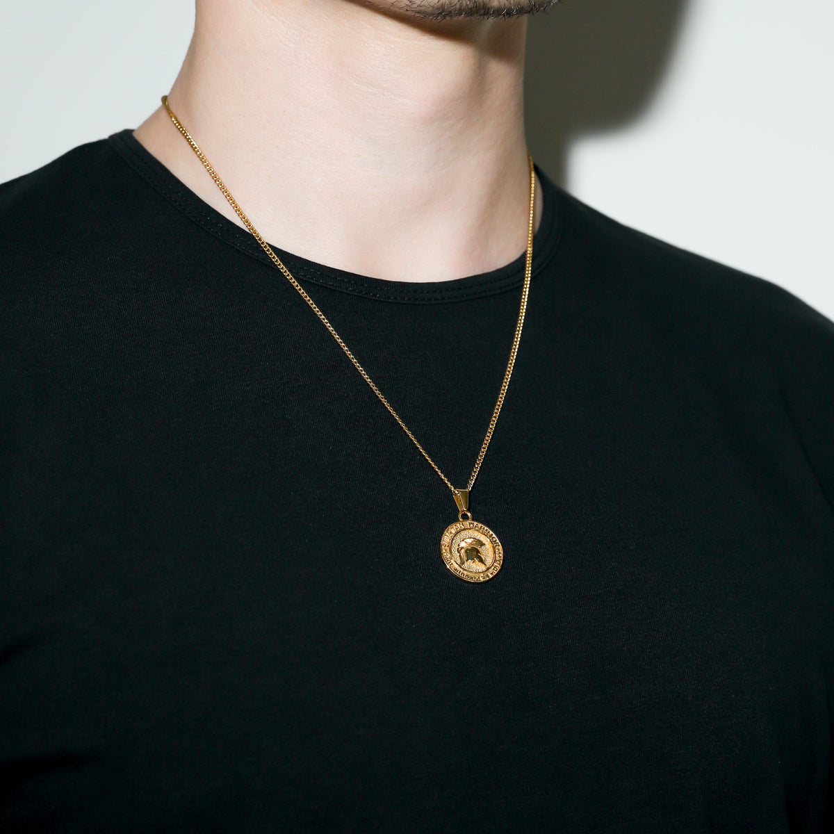Gold Spartan warrior pendant necklace with round shield-like emblem pendant.