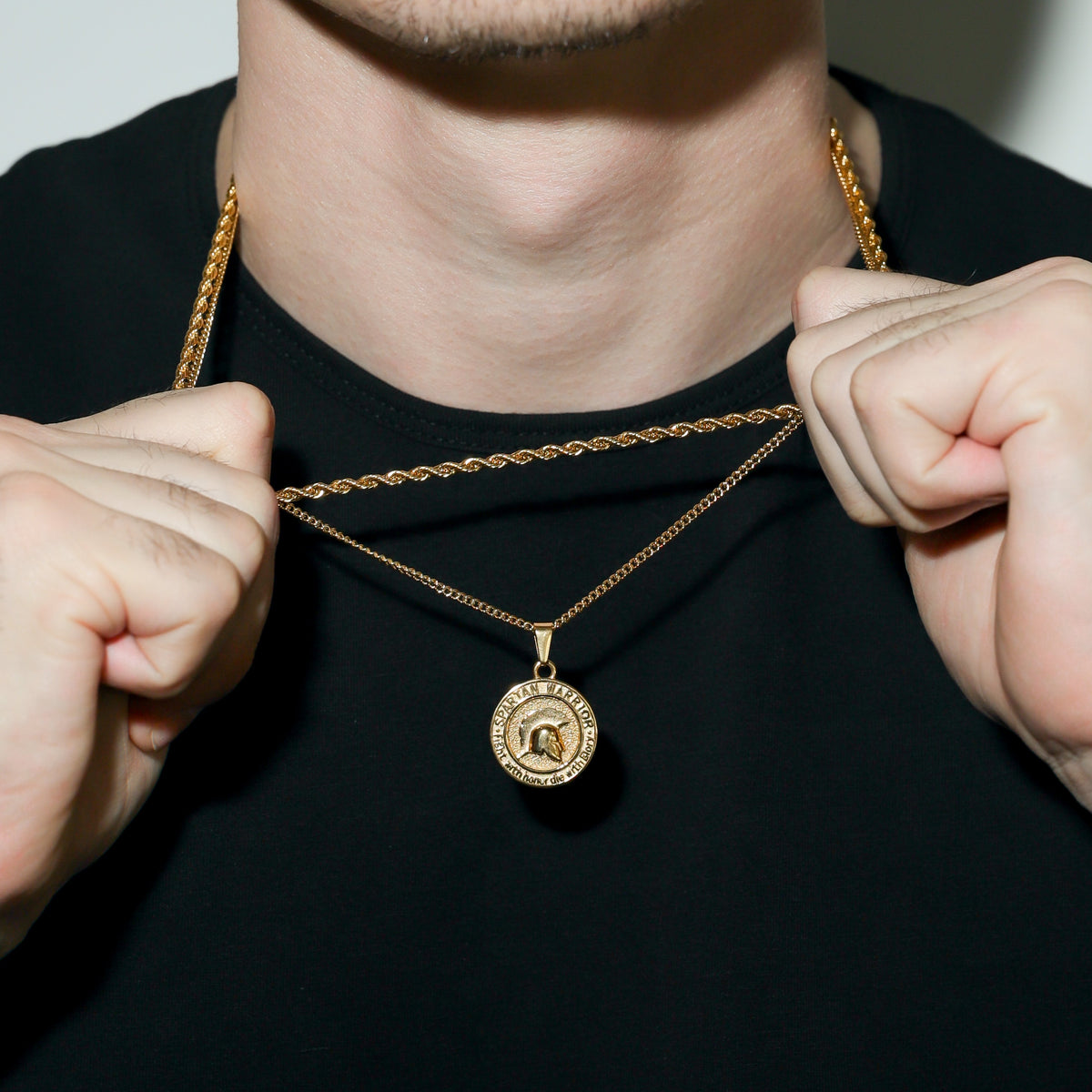 Gold Spartan warrior pendant necklace being adjusted at the neck with round emblem pendant.