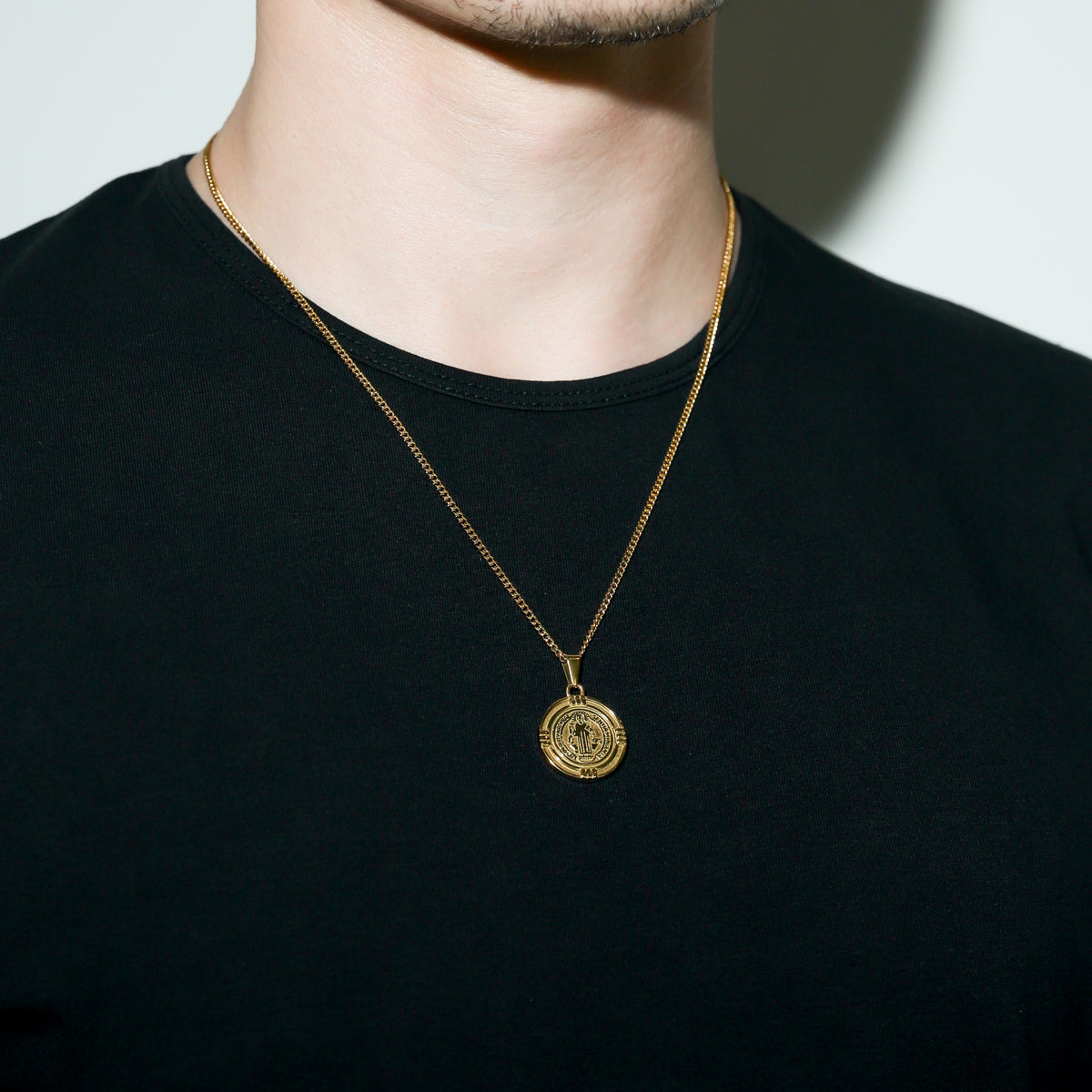 Gold Saint Benedict medal necklace with round medal pendant centered on chest