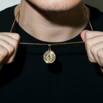 Gold Saint Benedict medal necklace clasp and round medal pendant held near collar