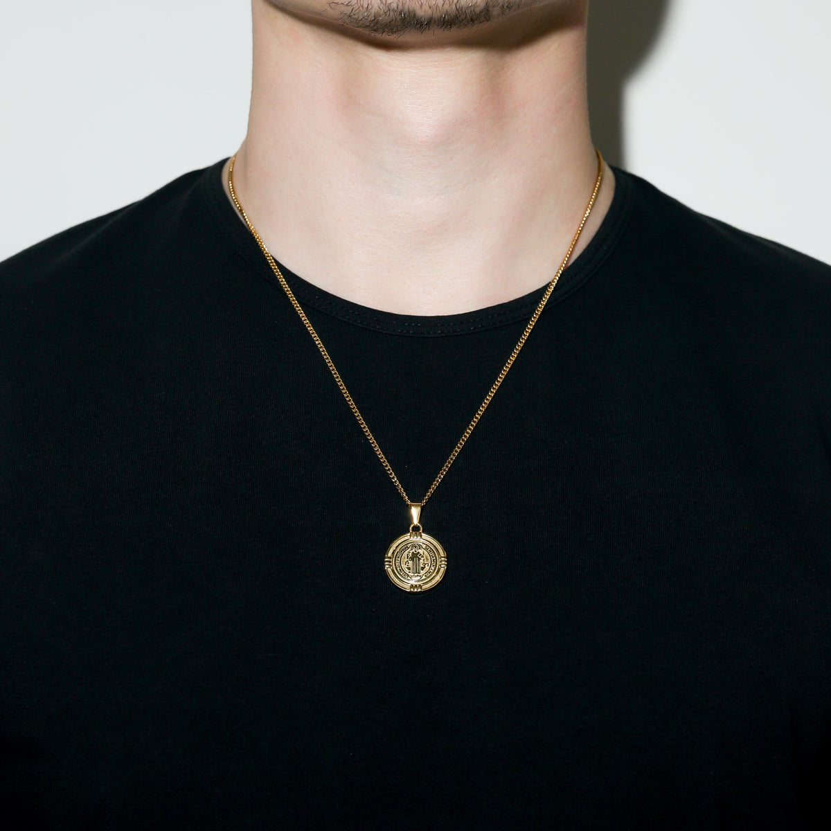 Gold Saint Benedict medal necklace on a man’s neck with round medal pendant