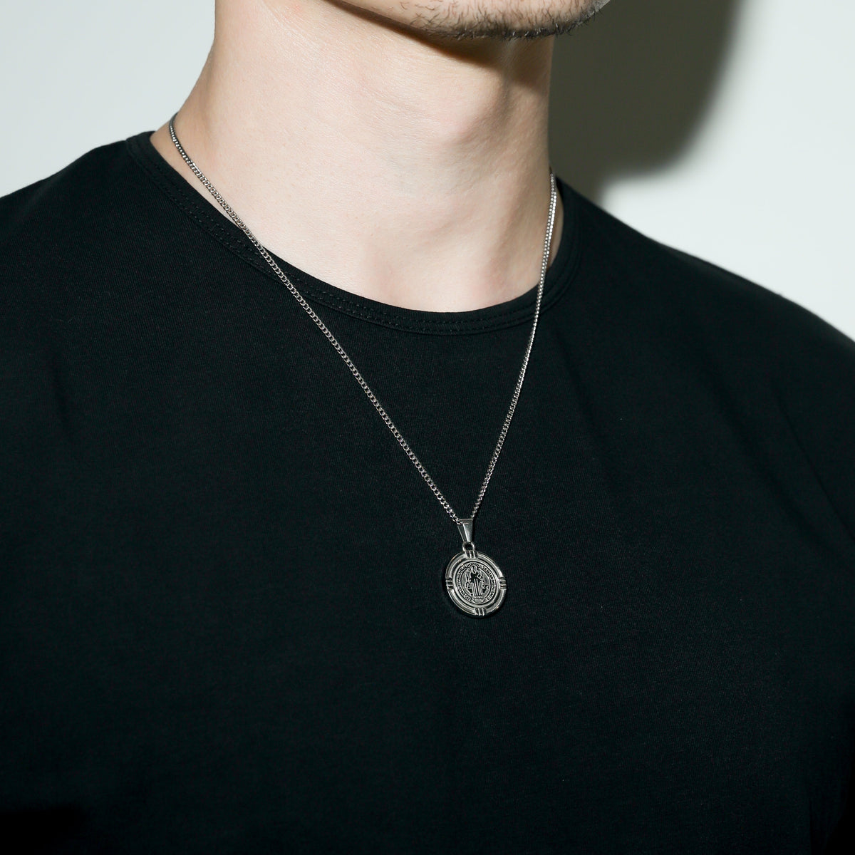 Silver Saint Benedict medal necklace close-up with round medal pendant on chest