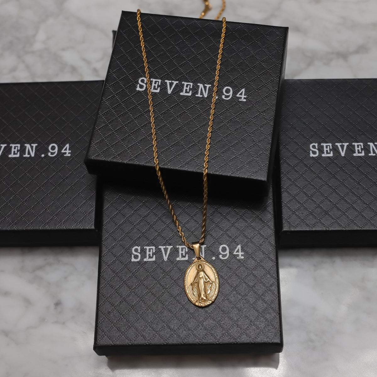 Gold Saint Mary pendant necklace with gift boxes, oval pendant visible