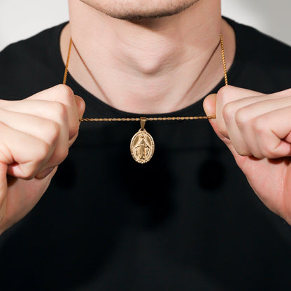 Gold Saint Mary pendant necklace close-up, hands holding chain at collar
