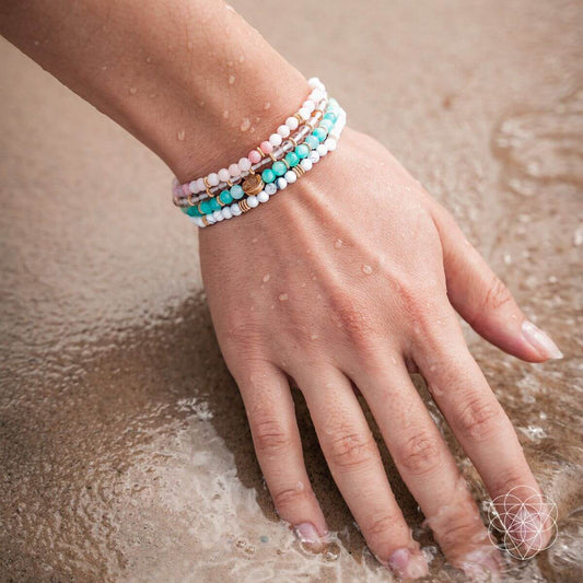 Turquoise and white beaded bracelets on wrist with small gold spacer beads