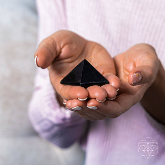 Black stress-soothing pyramid held in hands