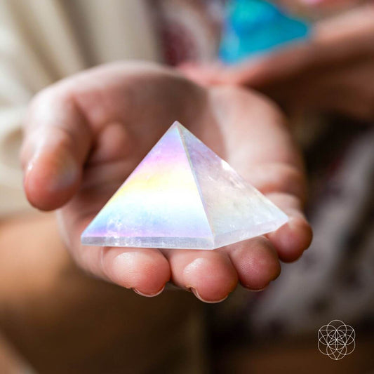 Rainbow iridescent crystal pyramid held in cupped hands