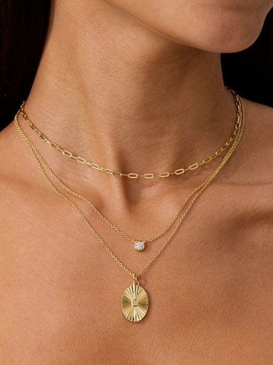 Gold layered sunburst pendant necklaces on delicate chains with small round charm