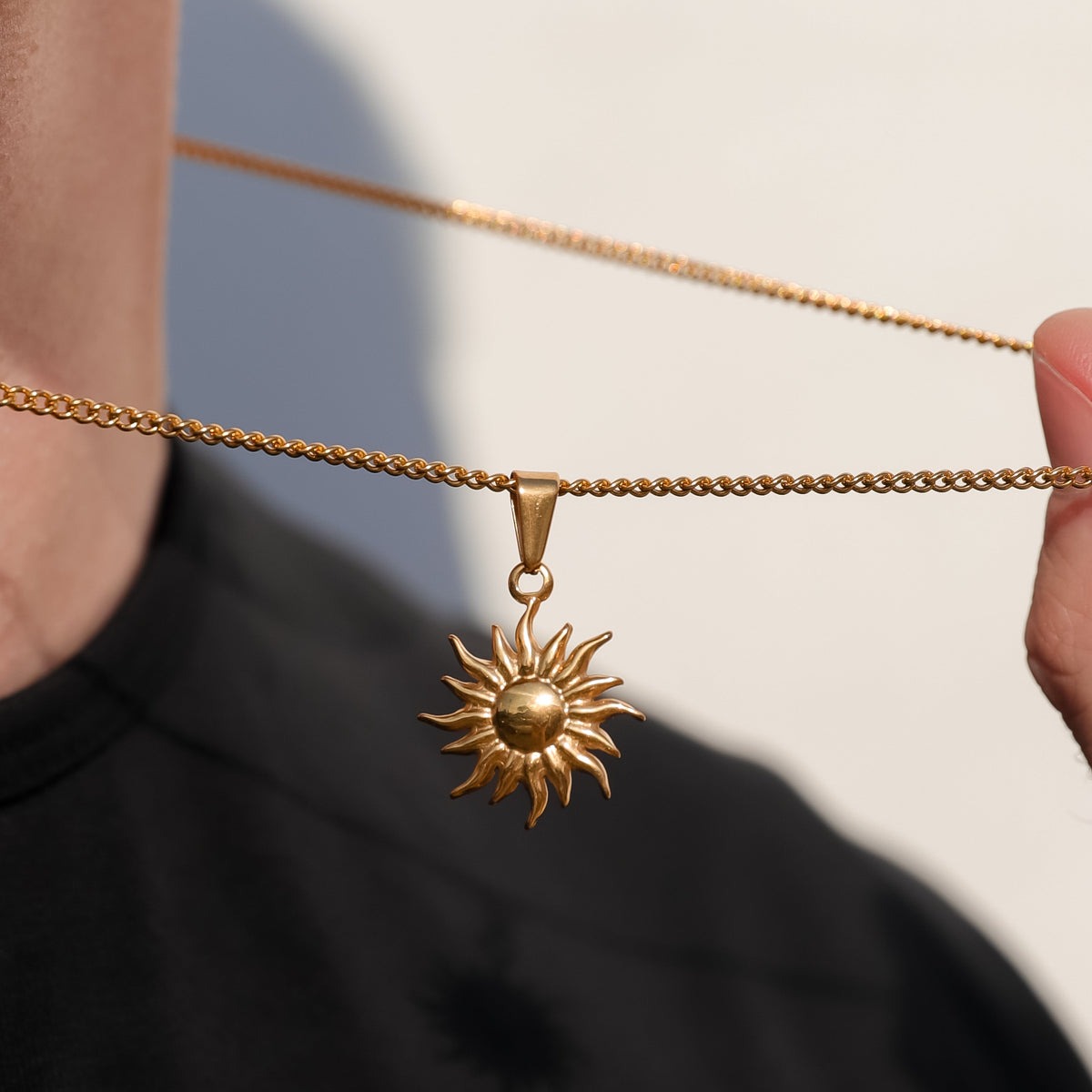 Gold chain necklace with sun pendant charm and round bail connector.