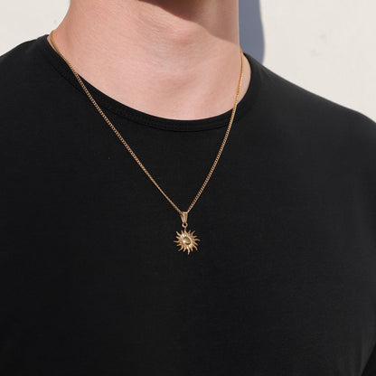 Gold sun pendant necklace with starburst charm and circular center detail.
