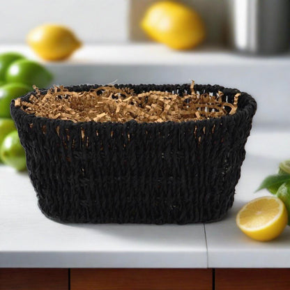 Black woven gift basket with open top and shredded filler on a white table.