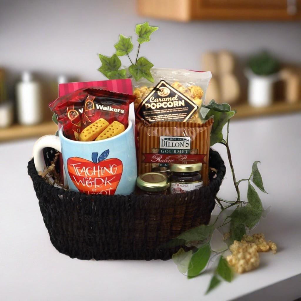 Gift basket with black woven basket, Teaching Work mug, and caramel popcorn snack packs.