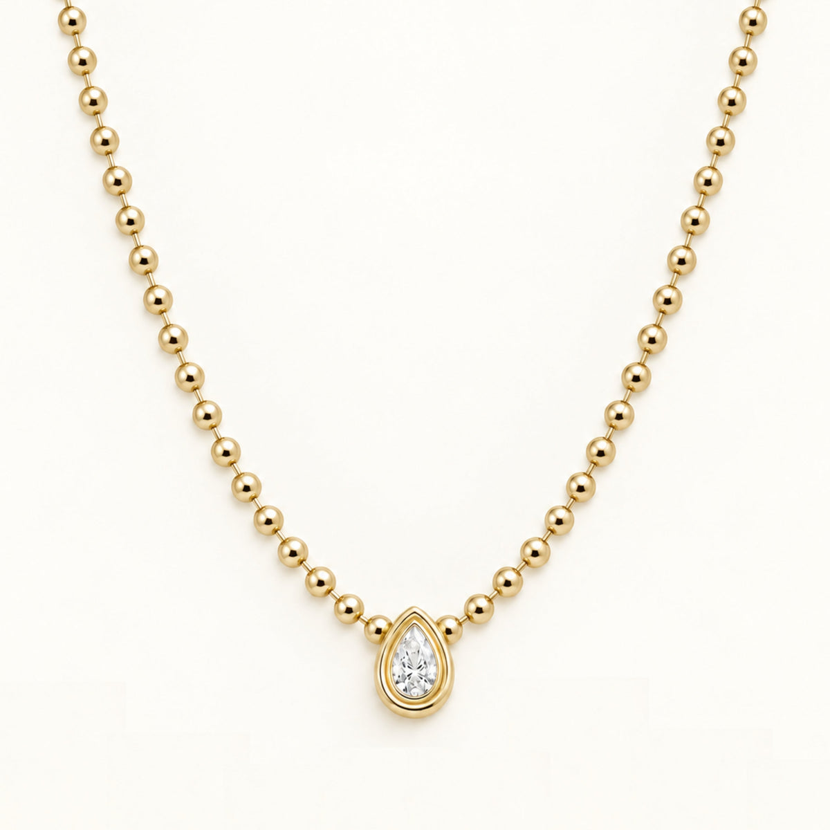 Gold ball-link chain necklace with teardrop diamond-style pendant, close-up front view
