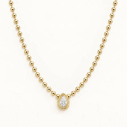 Gold ball-link chain necklace with teardrop diamond-style pendant, close-up front view