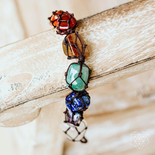 Beaded chakra tassel bracelet with multicolor stones and braided dark cord.