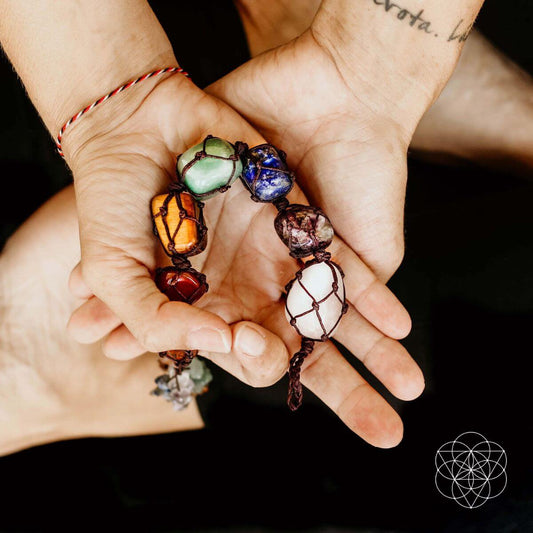 Beaded chakra tassel bracelets in multicolor stones held in hands.