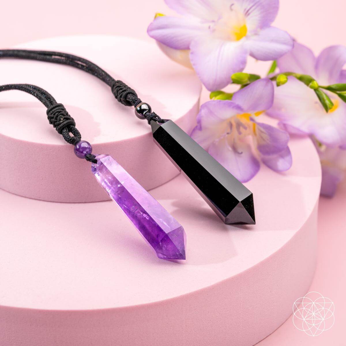 Two amethyst point pendant necklaces on black cord with purple beads