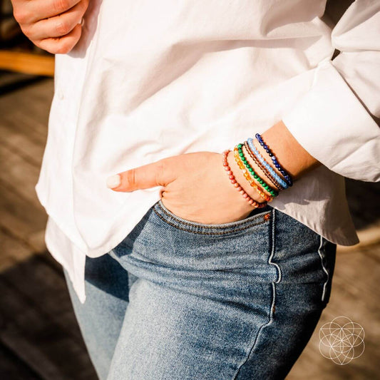 Colorful beaded chakra bracelets on wrist, stacked multi-band style.