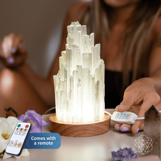 Cleanse-All selenite lamp glowing inside round wooden base with remote control beside it