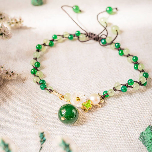 Green beaded anklet with large round green charm and gold floral accents.