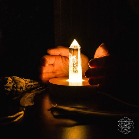 Crystal point lamp on round wooden base with warm glow near hands