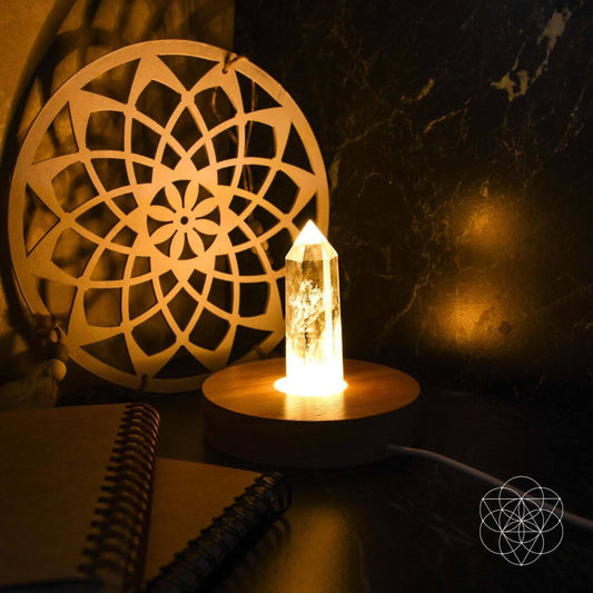 Crystal point lamp on round light-wood base with warm flame-like glow