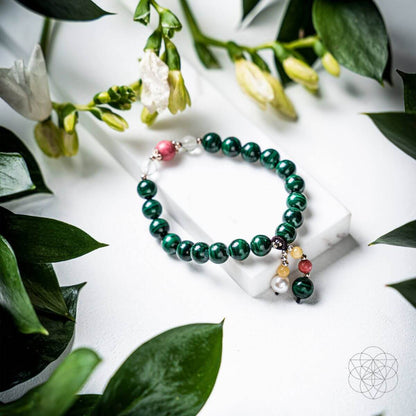Beaded bracelet with dark green beads and hanging charm accents, including pearl-like bead