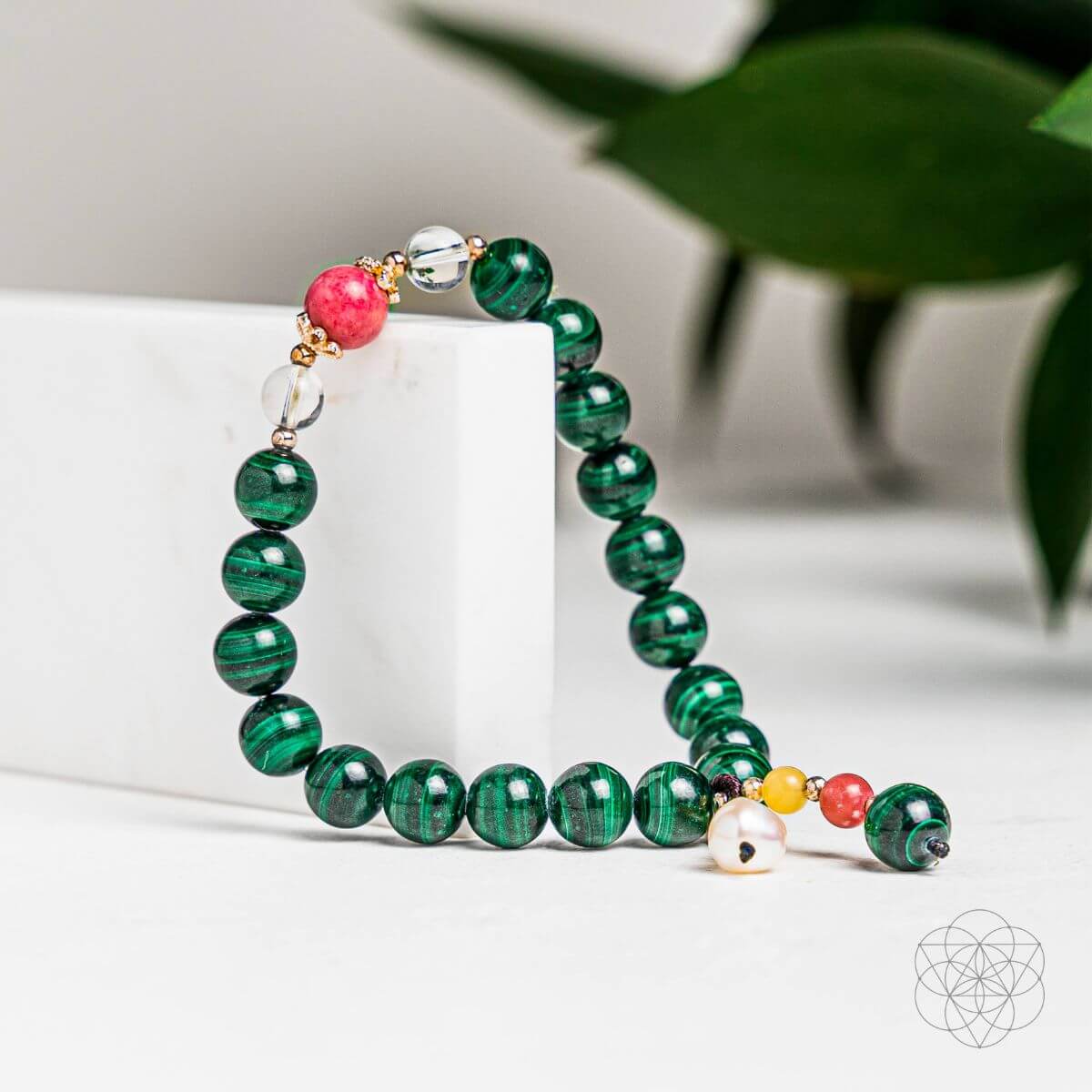 Beaded gemstone bracelet with green malachite-style beads, silver clasp, and small charms