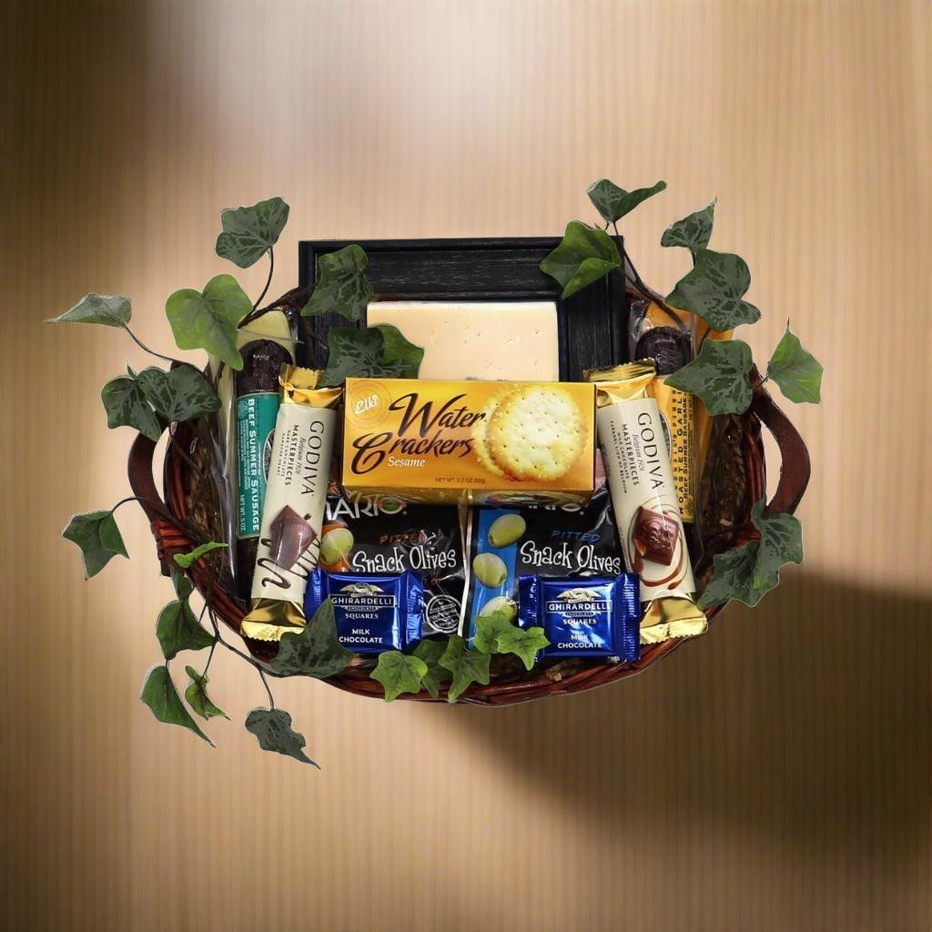 Sympathy gift basket with photo frame, crackers, olives, and chocolate bars in wicker basket