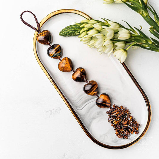 Beaded tassel charm with amber-brown striped heart beads and braided cord loop