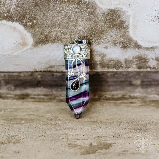 Purple-blue crystal-point pendant with silver frame and round cabochon