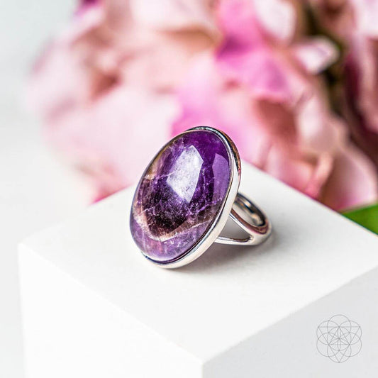 Oval purple gemstone ring with silver band and reflective facet bezel