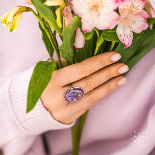 Purple oval gemstone ring on hand against floral bouquet