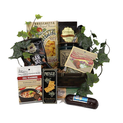 Gift basket with assorted snack boxes, crackers, and bottle, surrounded by green vines