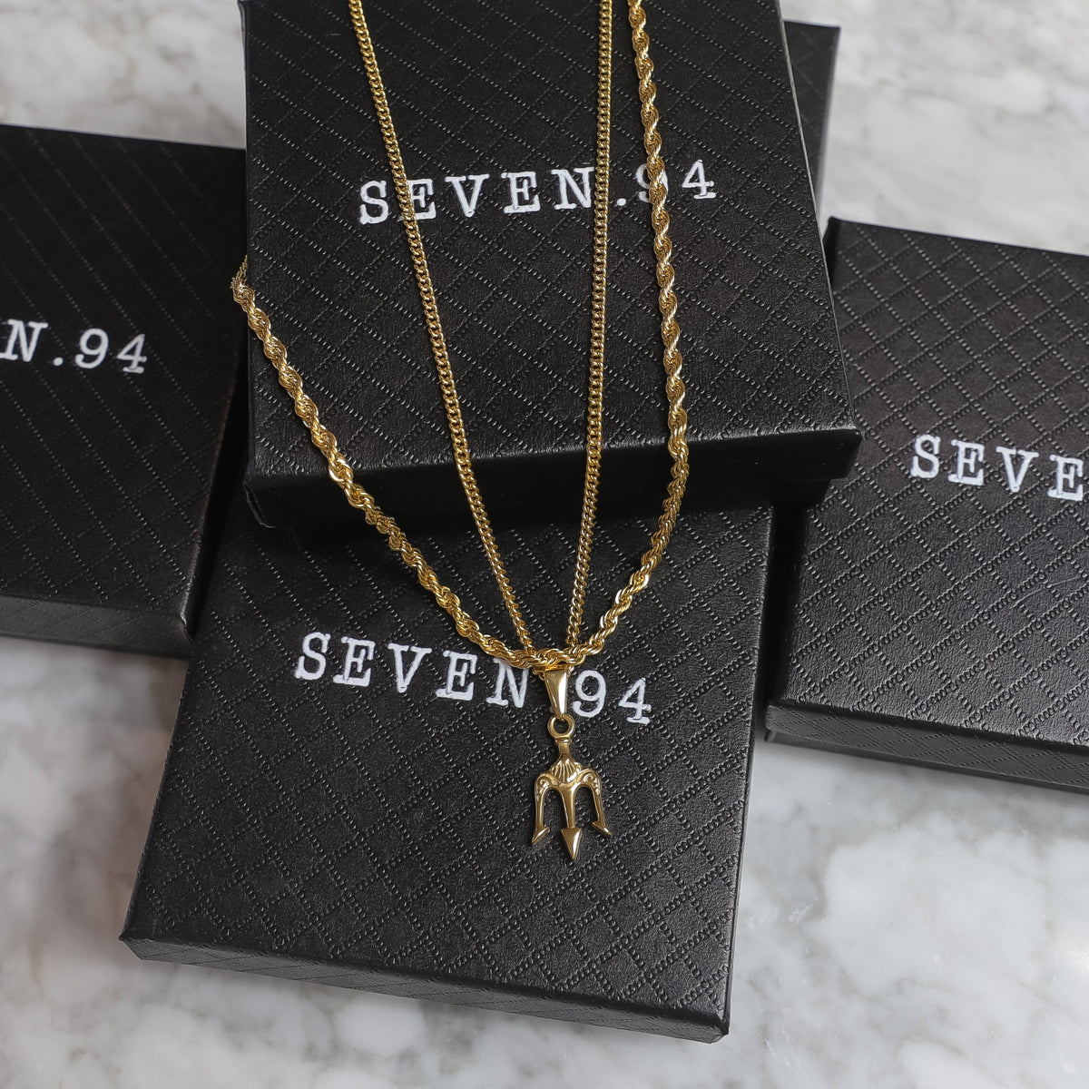 Gold trident pendant necklace set shown with gift boxes
