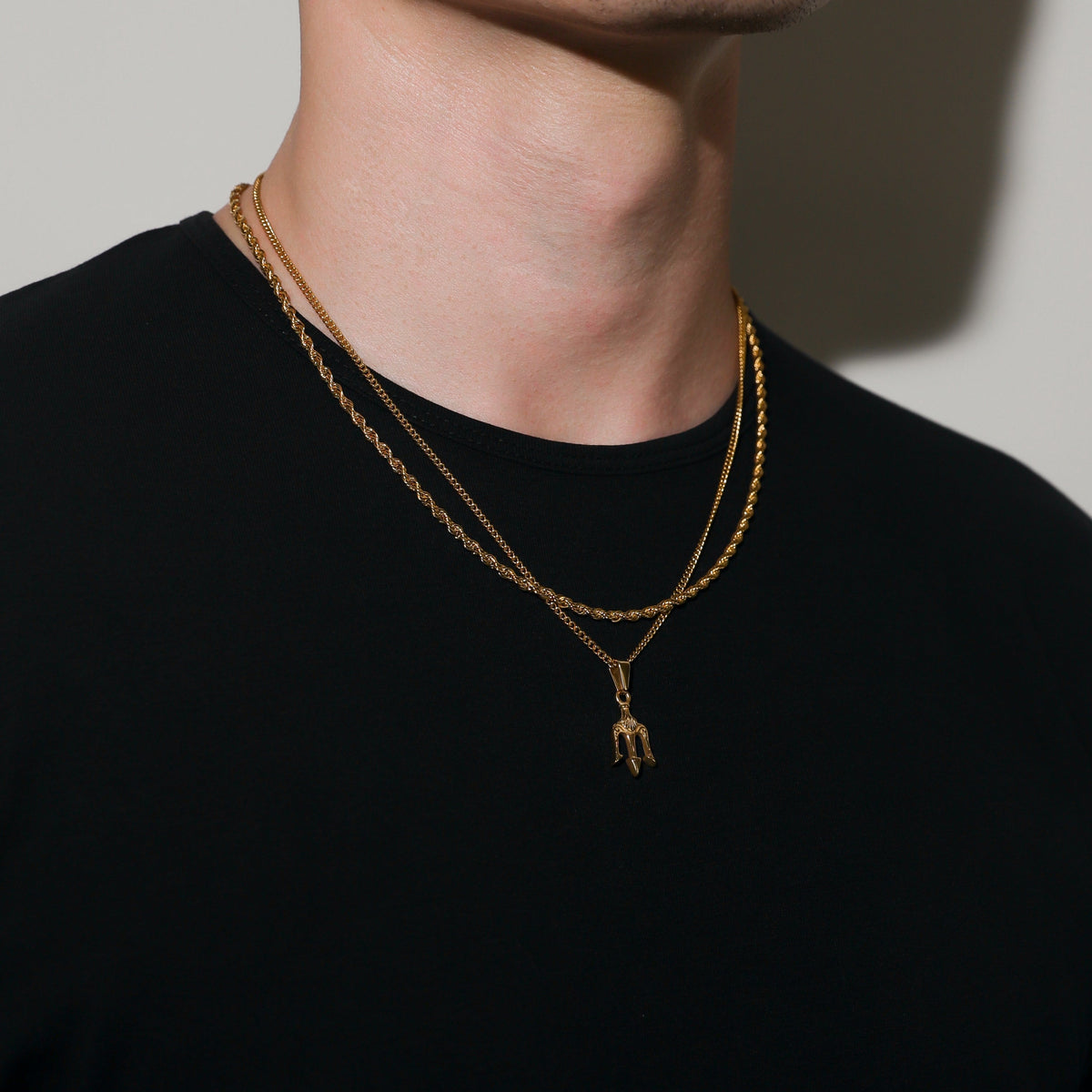 Gold layered necklace with trident charm pendant on center chain