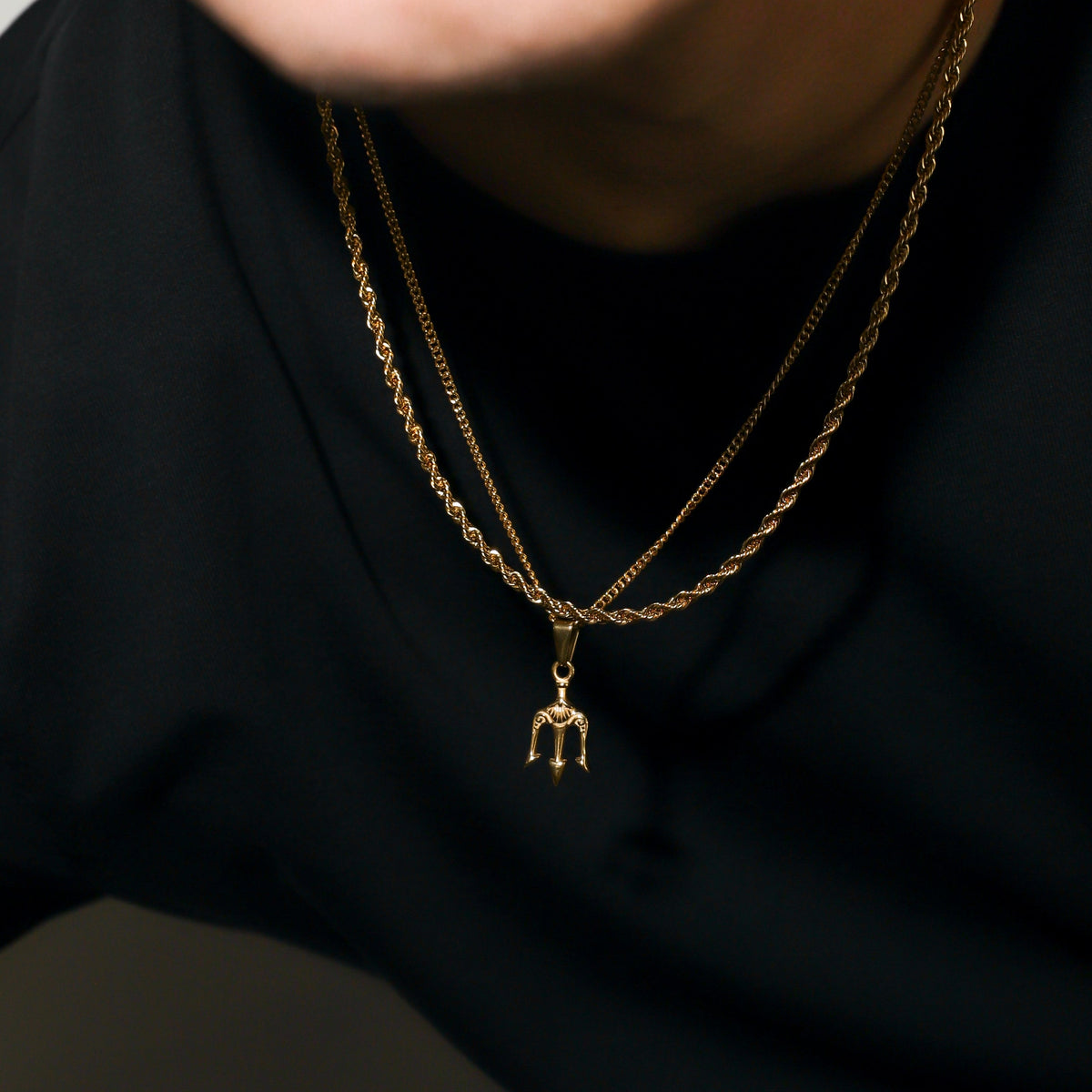 Gold two-chain necklace with trident pendant on short center chain
