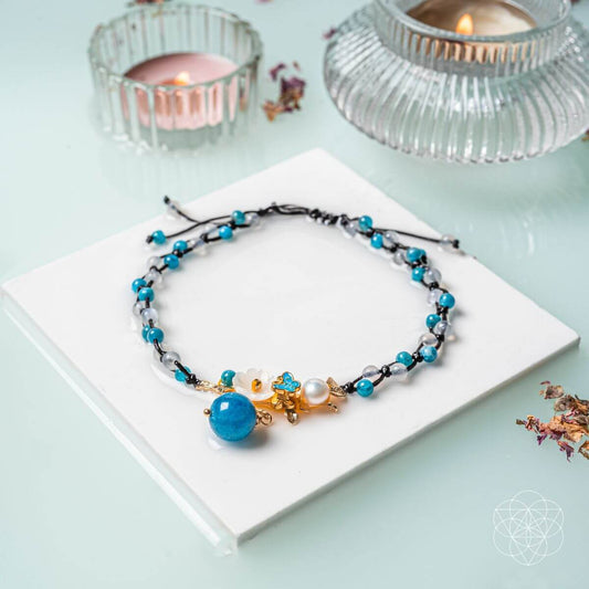 Blue beaded anklet with gold charm and pearl accent on black cord