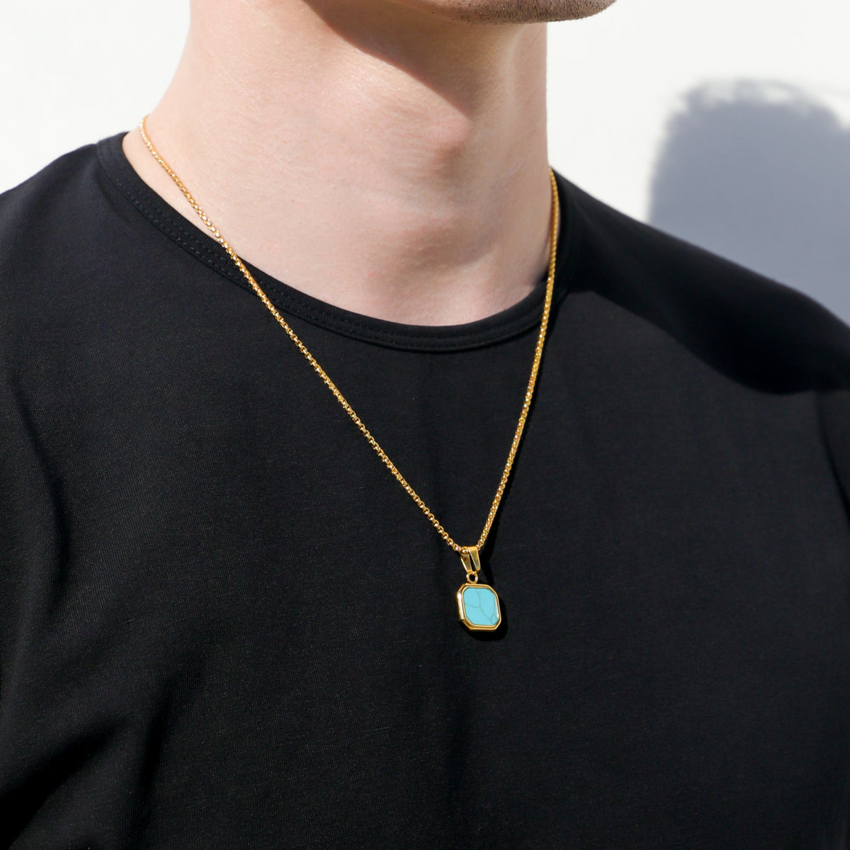 Gold-tone necklace featuring a turquoise square stone pendant at chest level