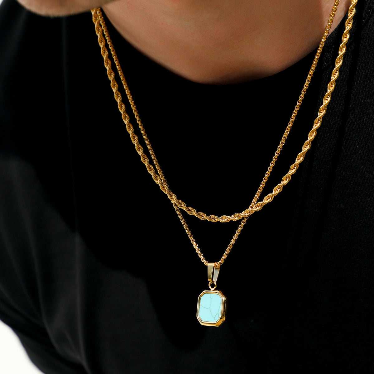 Close-up of gold-tone necklace with turquoise square stone pendant