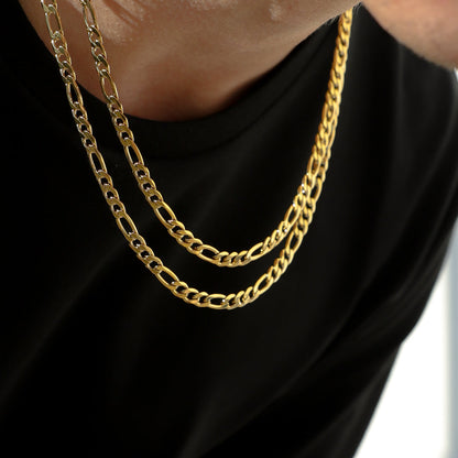 Gold-tone Figaro chain necklace layered on neck, oval links