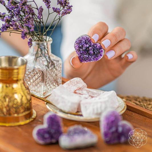 Purple amethyst heart cluster held in a hand, natural crystal sparkle.