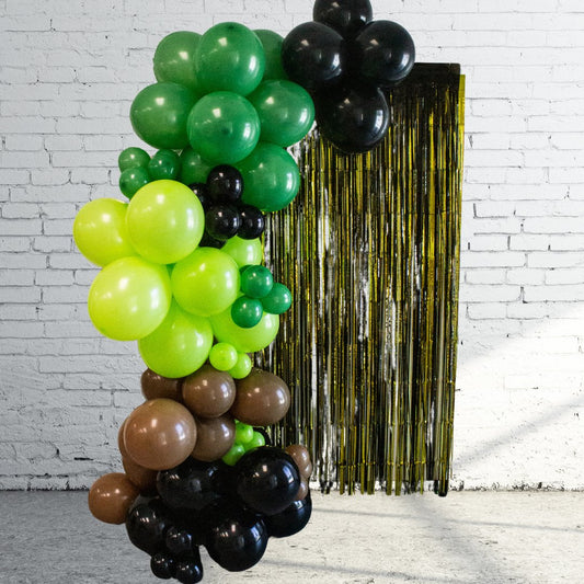 Balloon garland display with green, lime, brown, and black balloons plus gold tinsel