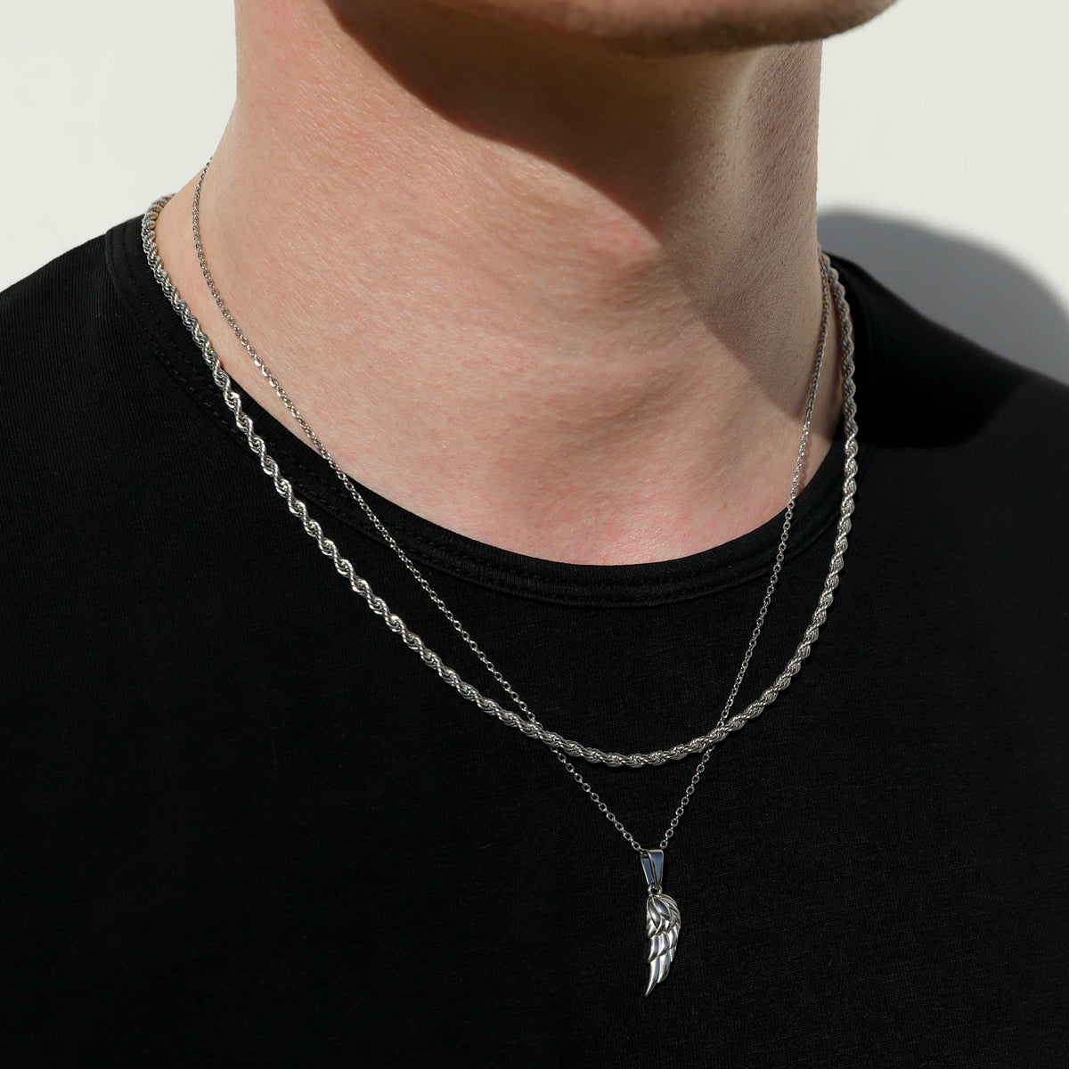 Close-up of silver angel wing pendant on twist rope chain