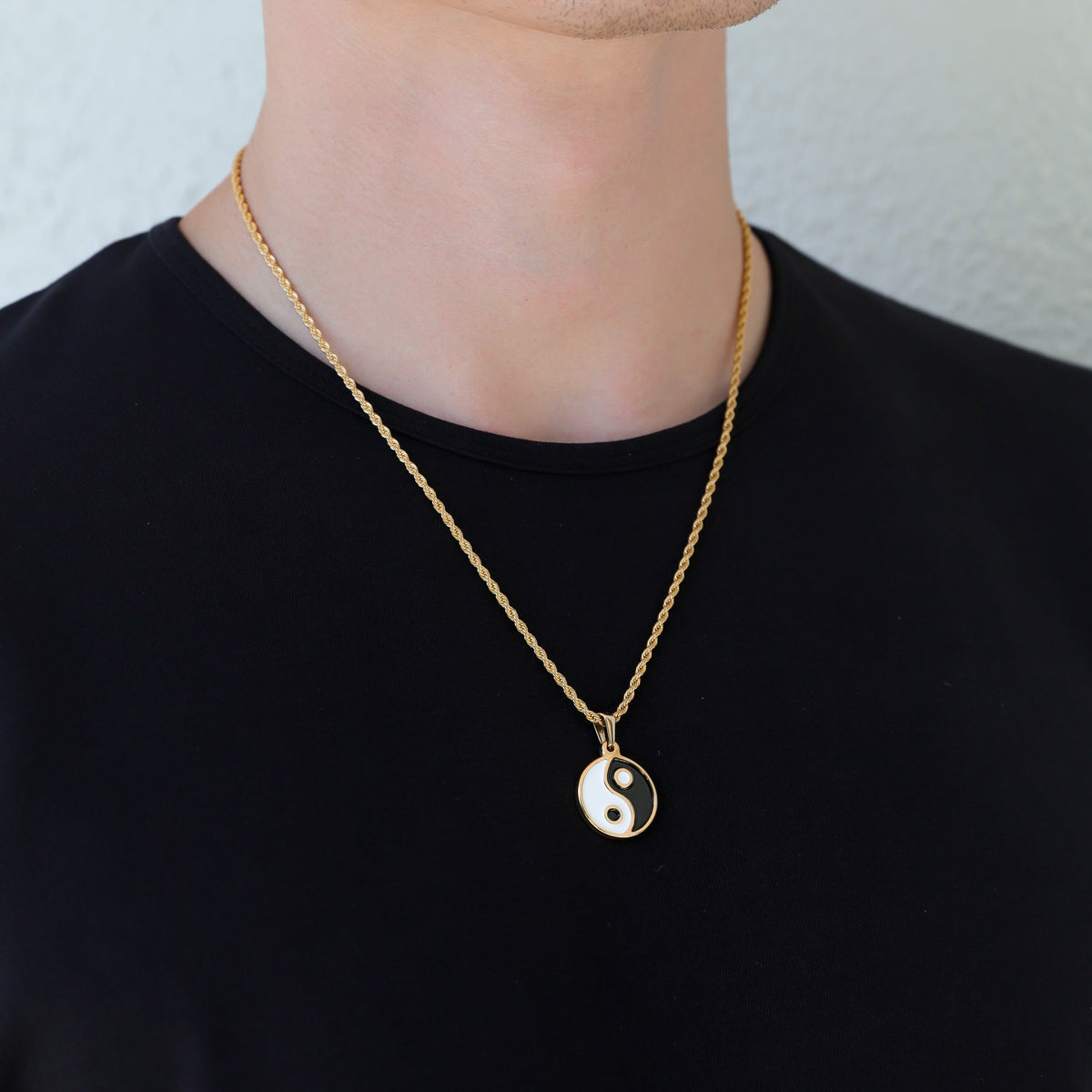 Gold yin yang pendant necklace shown on neckline with black and white enamel pendant