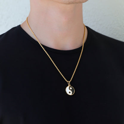Gold yin yang pendant necklace shown on neckline with black and white enamel pendant
