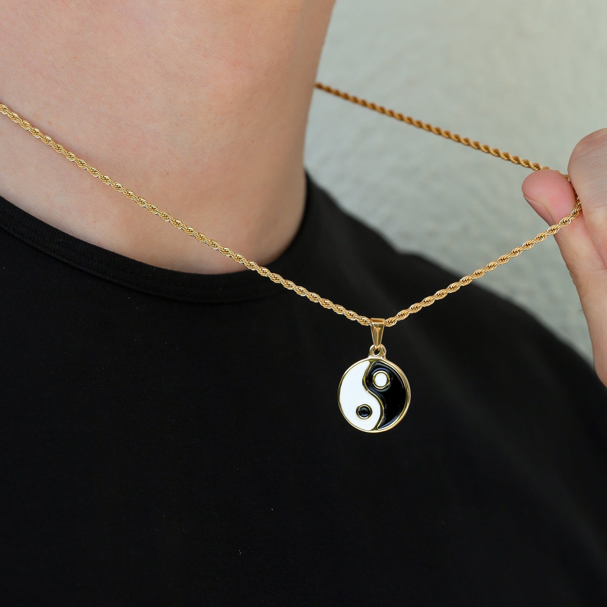 Gold chain with yin yang pendant at neckline; black and white enamel charm