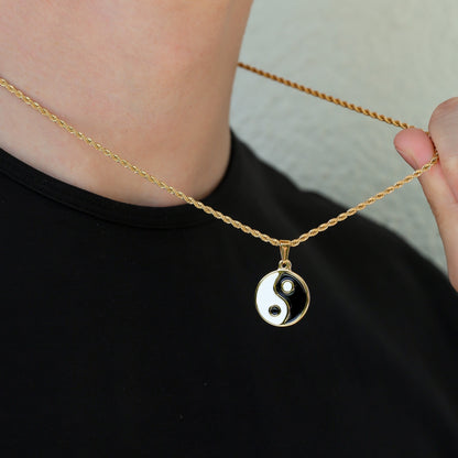 Gold chain with yin yang pendant at neckline; black and white enamel charm