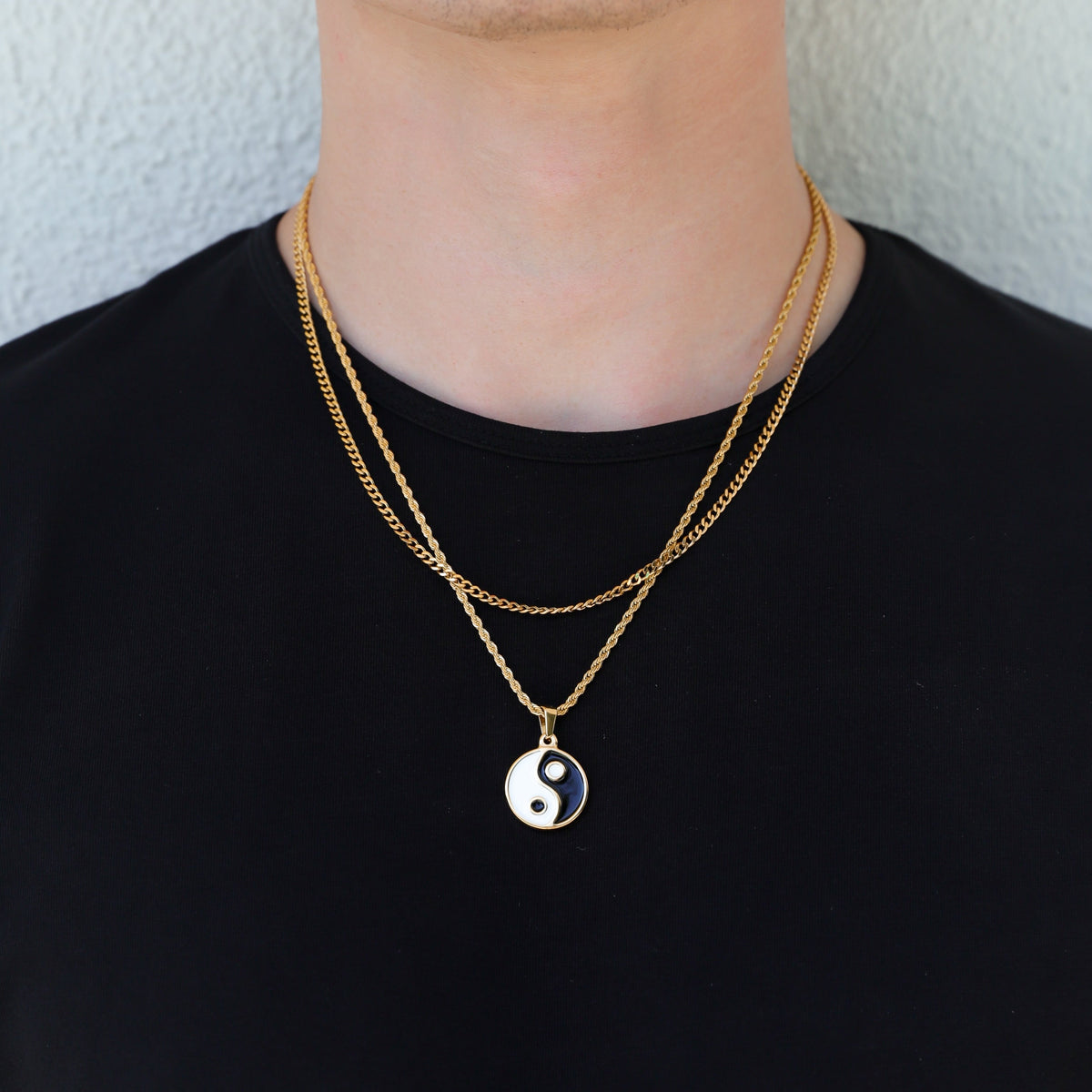 Gold yin yang pendant necklace on black shirt; small round enamel charm in contrast